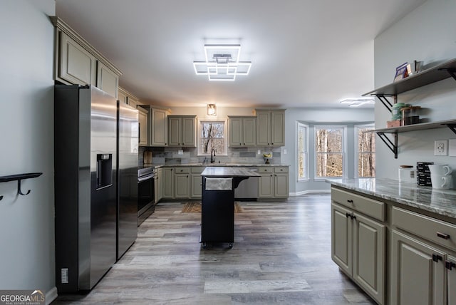 kitchen with appliances with stainless steel finishes, a healthy amount of sunlight, a sink, and gray cabinetry