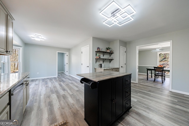 kitchen with light wood-style flooring, dark cabinets, baseboards, stainless steel dishwasher, and open shelves