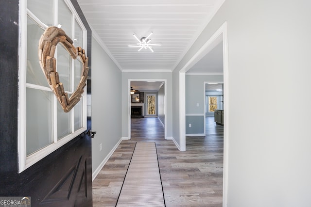 hallway featuring crown molding, baseboards, and wood finished floors