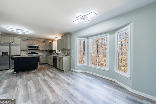 kitchen with appliances with stainless steel finishes, a sink, gray cabinets, light countertops, and backsplash