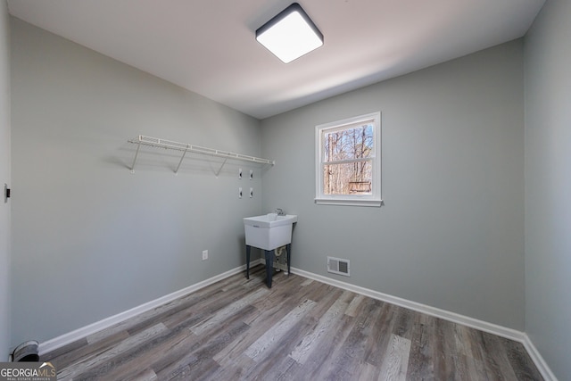 washroom featuring laundry area, visible vents, baseboards, and wood finished floors