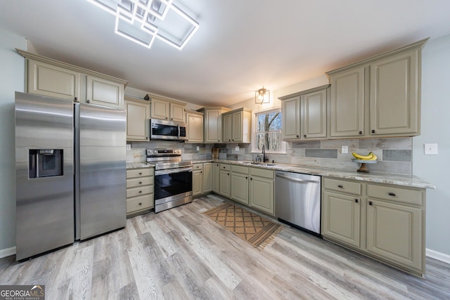 kitchen with light wood finished floors, tasteful backsplash, appliances with stainless steel finishes, cream cabinetry, and a sink