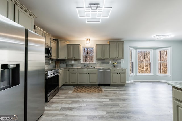 kitchen featuring appliances with stainless steel finishes, a healthy amount of sunlight, a sink, and gray cabinetry