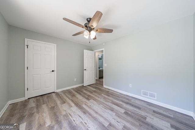 unfurnished bedroom with a ceiling fan, baseboards, visible vents, and wood finished floors