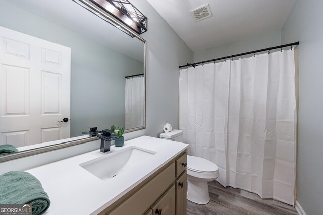 bathroom featuring curtained shower, visible vents, toilet, vanity, and wood finished floors