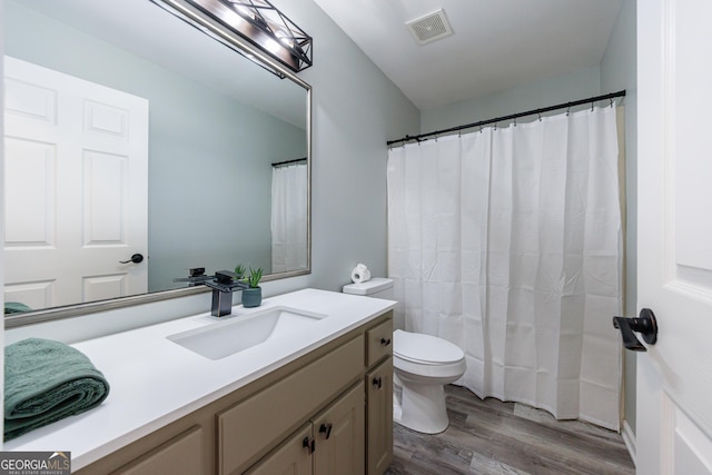 bathroom with visible vents, toilet, a shower with curtain, wood finished floors, and vanity