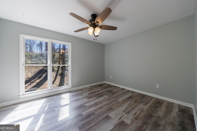 empty room with wood finished floors, a ceiling fan, and baseboards