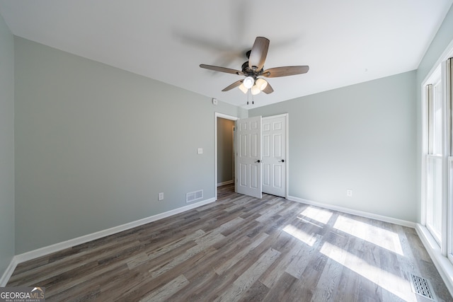 unfurnished room featuring a ceiling fan, visible vents, baseboards, and wood finished floors