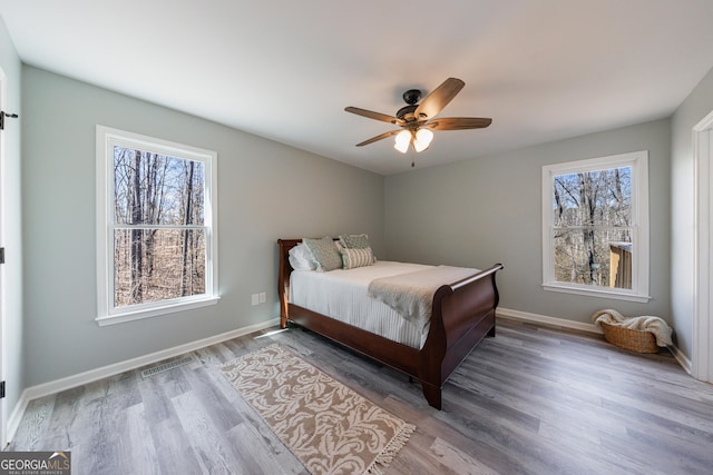 bedroom with visible vents, multiple windows, baseboards, and wood finished floors