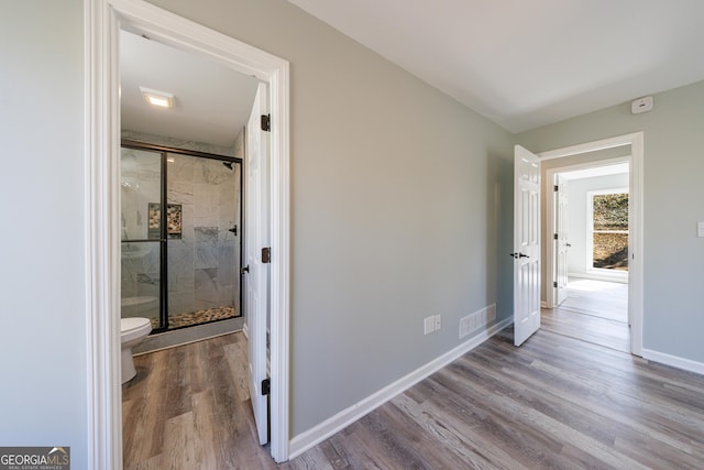 corridor with wood finished floors, visible vents, and baseboards