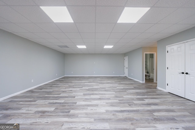 finished basement featuring baseboards, a drop ceiling, and wood finished floors