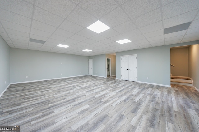 finished below grade area featuring a paneled ceiling, baseboards, and wood finished floors