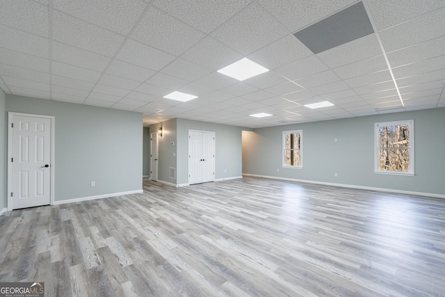 unfurnished room with baseboards, a drop ceiling, and wood finished floors