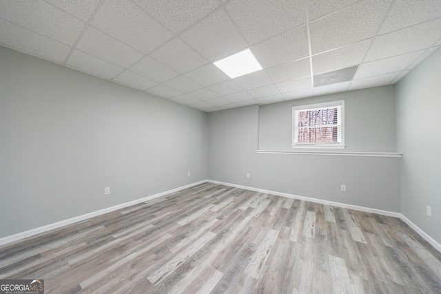 spare room with a paneled ceiling, baseboards, and wood finished floors