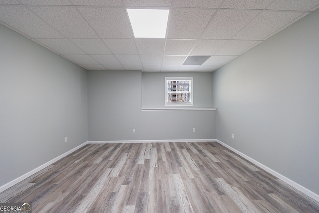 unfurnished room featuring a drop ceiling, wood finished floors, and baseboards