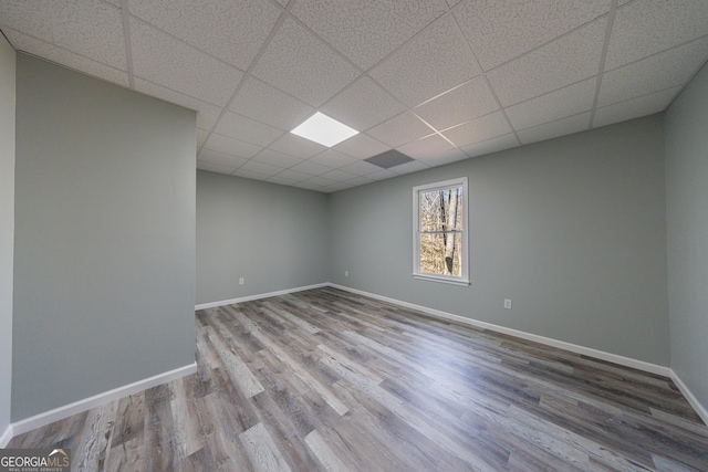 spare room with a paneled ceiling, baseboards, and wood finished floors