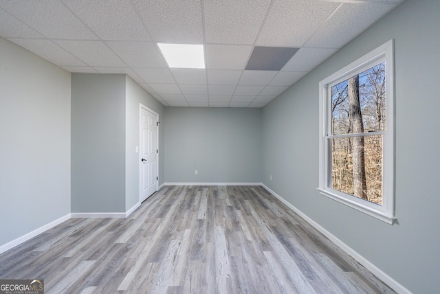 interior space with baseboards, a drop ceiling, and wood finished floors