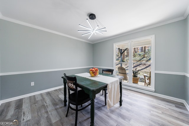 dining space featuring a chandelier, crown molding, baseboards, and wood finished floors