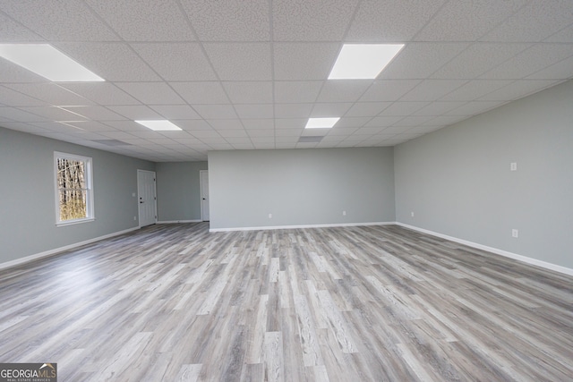 below grade area with wood finished floors, a paneled ceiling, and baseboards