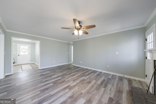 unfurnished living room featuring ornamental molding, a brick fireplace, baseboards, and wood finished floors