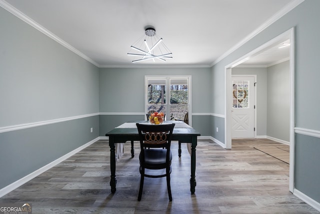 dining room with an inviting chandelier, crown molding, baseboards, and wood finished floors