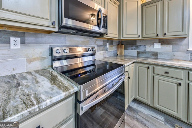 kitchen featuring stainless steel appliances, backsplash, light stone countertops, and light wood-style floors