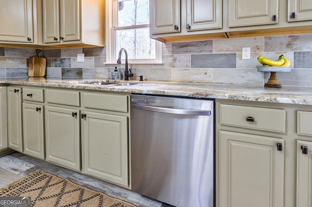 kitchen with dishwasher, cream cabinetry, a sink, and tasteful backsplash