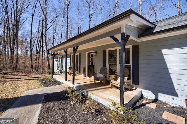 entrance to property featuring covered porch and a shingled roof