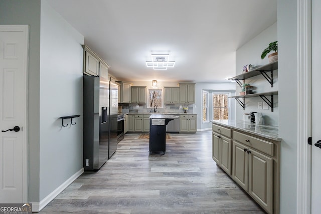 kitchen with appliances with stainless steel finishes, gray cabinets, light wood-style floors, open shelves, and a sink