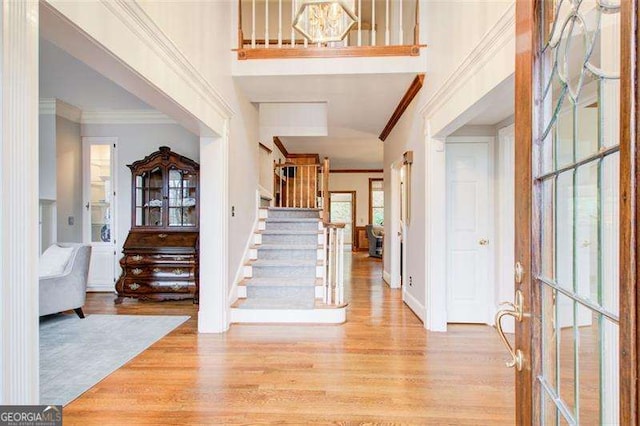 foyer with ornamental molding and light hardwood / wood-style flooring