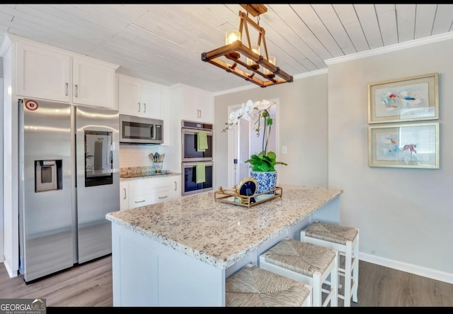 kitchen featuring stainless steel appliances, ornamental molding, light stone counters, white cabinets, and pendant lighting