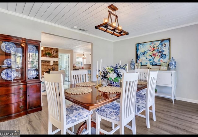 dining space with wooden ceiling, light hardwood / wood-style floors, crown molding, and a notable chandelier