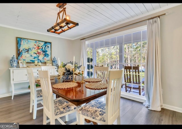 dining area with dark wood-type flooring, crown molding, and a notable chandelier