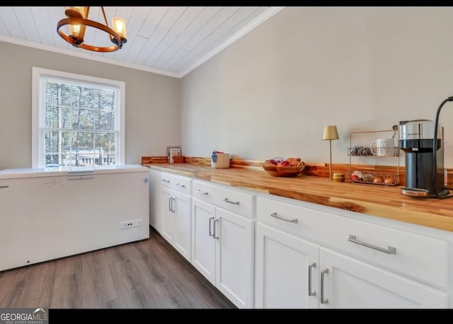 kitchen with wood counters, hanging light fixtures, white cabinets, and ornamental molding