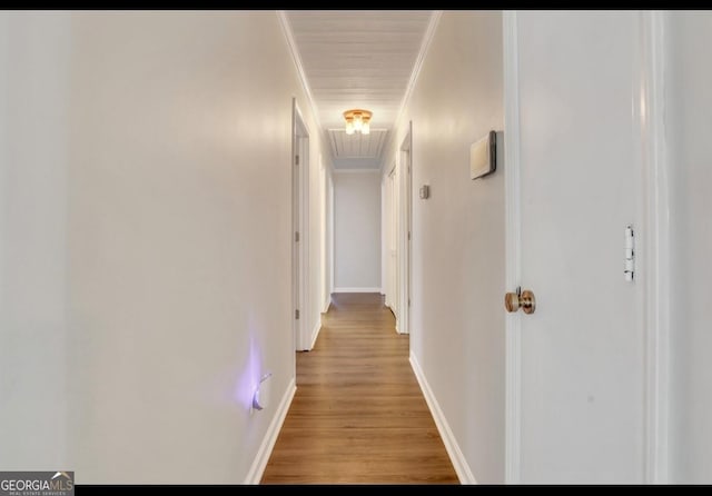 hallway with light wood-type flooring and crown molding