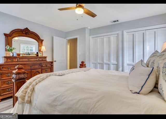 bedroom with ceiling fan and two closets