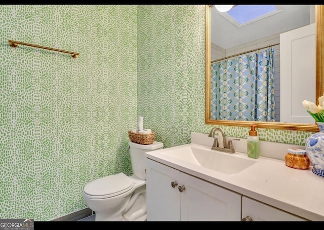 bathroom featuring toilet, a skylight, walk in shower, and vanity