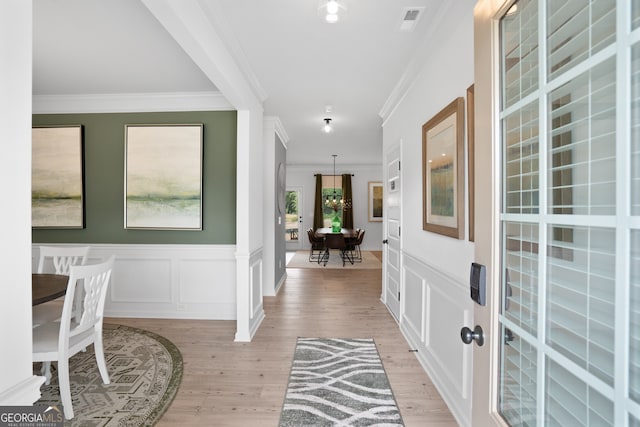 entryway with light hardwood / wood-style floors and crown molding