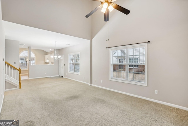 2414 Clock Face Ct, Lawrenceville, GA 30043 - unfurnished living room featuring a chandelier, ceiling fan, carpet flooring, and a towering ceiling