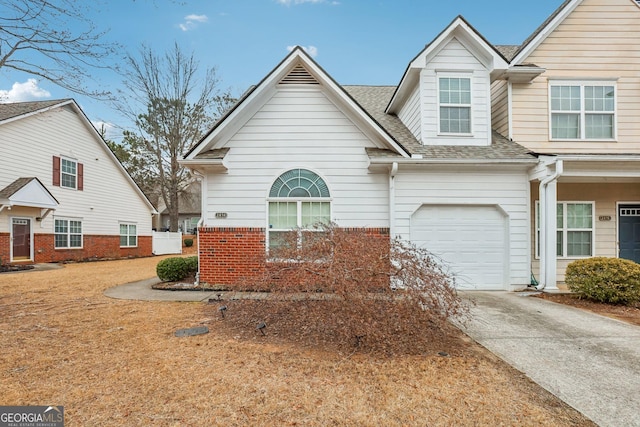 view of front of home featuring driveway, a shingled roof, a garage, and brick siding