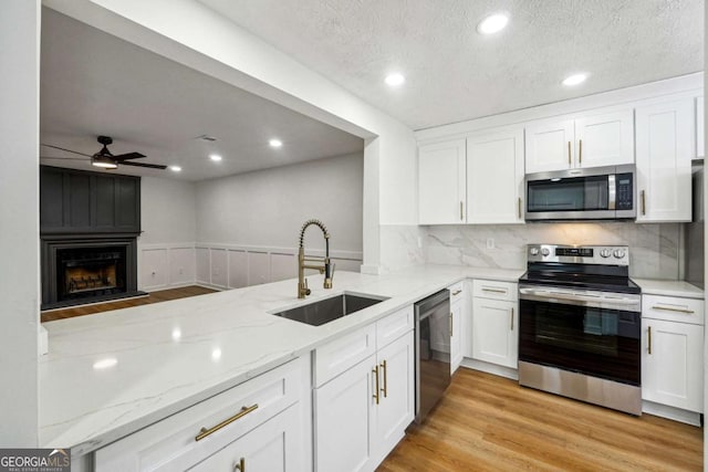 kitchen with appliances with stainless steel finishes, white cabinets, sink, and kitchen peninsula