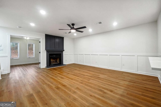 unfurnished living room featuring a fireplace, ceiling fan, and wood-type flooring