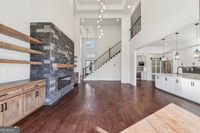 unfurnished living room with sink, dark wood-type flooring, a high ceiling, and beverage cooler