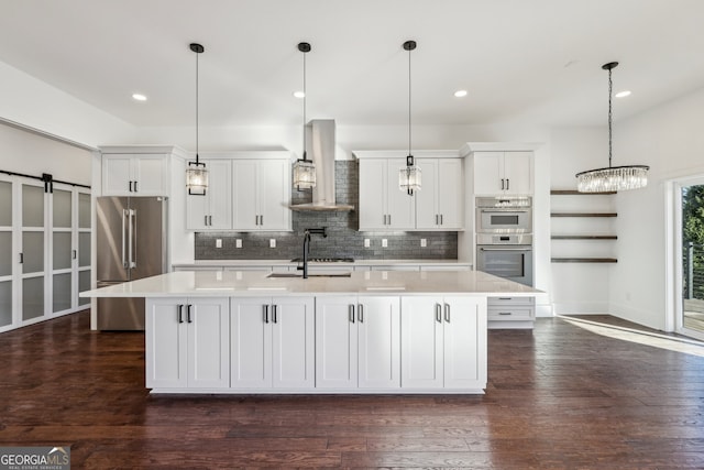 kitchen featuring stainless steel appliances, a kitchen island with sink, hanging light fixtures, and range hood