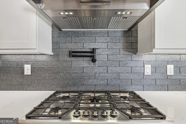 kitchen featuring gas cooktop, white cabinets, and backsplash