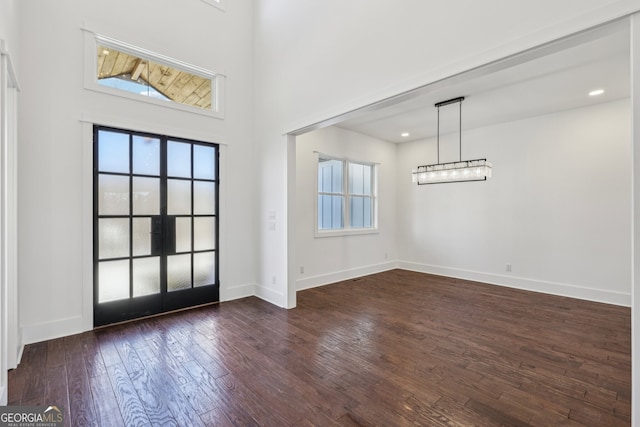 entrance foyer featuring plenty of natural light, dark hardwood / wood-style floors, and a towering ceiling