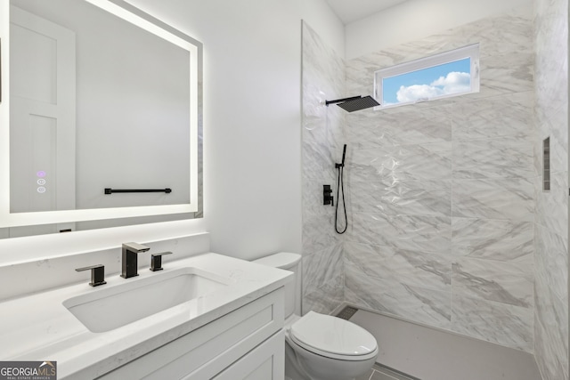 bathroom with vanity, a tile shower, and toilet