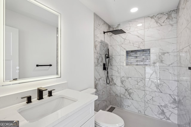 bathroom featuring toilet, vanity, and tiled shower