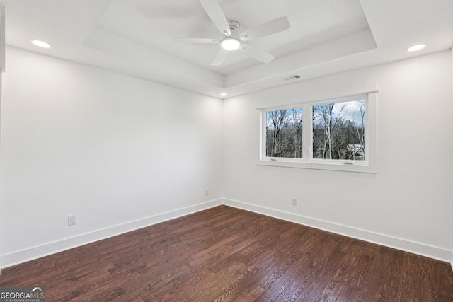 unfurnished room with ceiling fan, a raised ceiling, and dark hardwood / wood-style floors