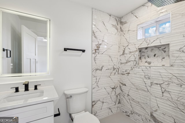 bathroom with vanity, tiled shower, and toilet